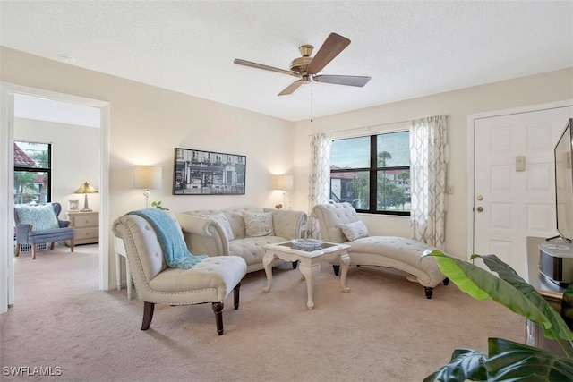 carpeted living room featuring a textured ceiling and ceiling fan