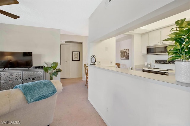 kitchen featuring electric stove, ceiling fan, white cabinetry, light carpet, and kitchen peninsula