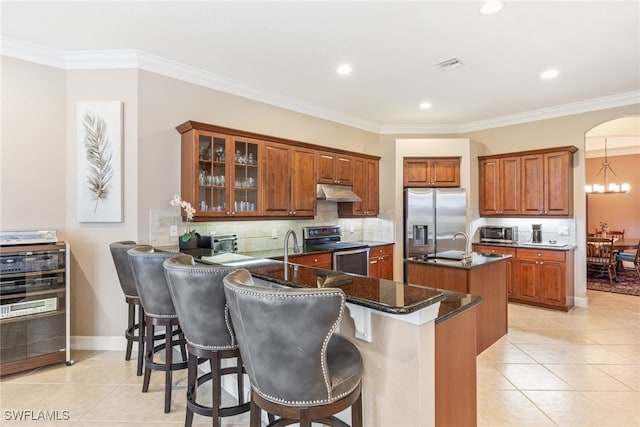 5683 Whispering Willow Way, Fort Myers, FL 33908 - kitchen with stainless steel appliances, under cabinet range hood, light tile patterned flooring, an island with sink, and brown cabinets