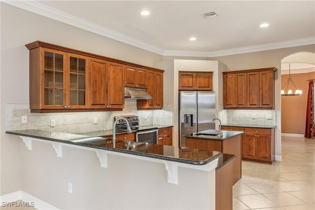 5683 Whispering Willow Way, Fort Myers, FL 33908 - kitchen featuring appliances with stainless steel finishes, under cabinet range hood, a peninsula, brown cabinetry, and crown molding