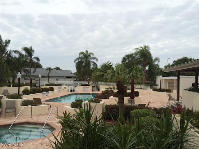 view of swimming pool featuring a hot tub and a patio