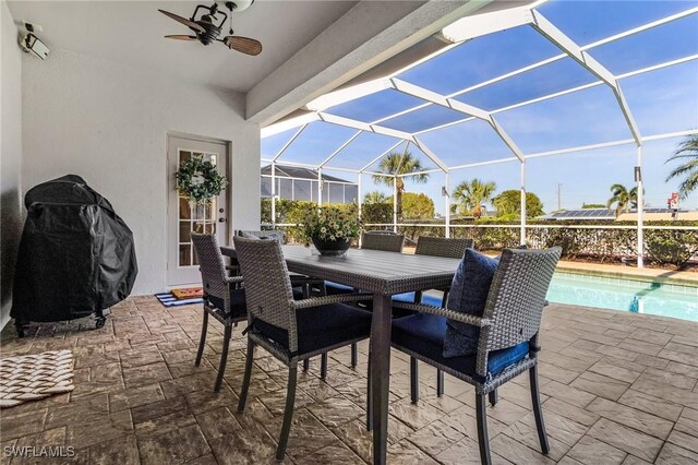 view of patio with ceiling fan, a grill, and glass enclosure