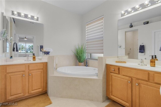 bathroom featuring a relaxing tiled tub, vanity, tile patterned floors, and ceiling fan