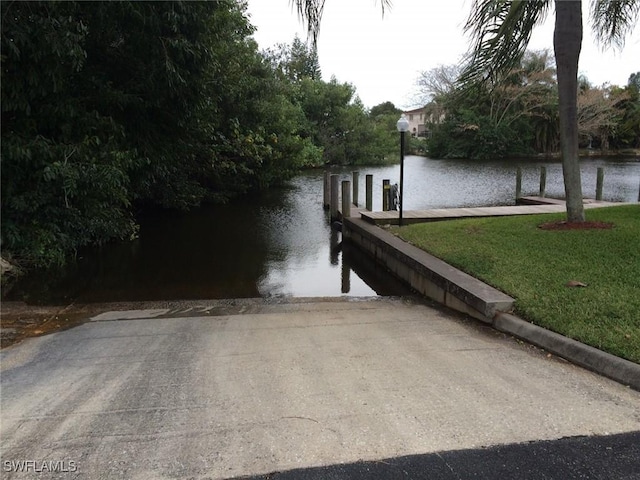 view of dock with a water view and a yard