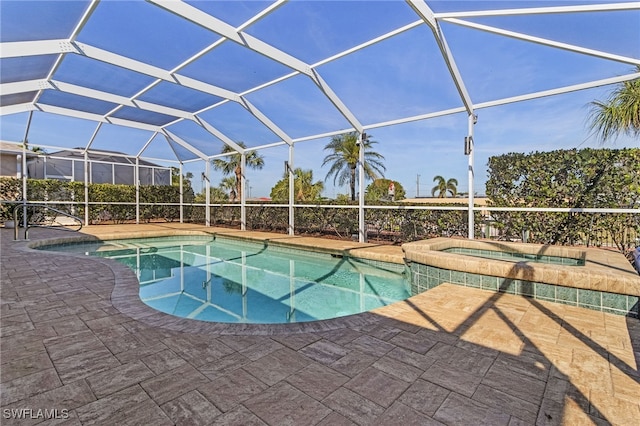 view of pool with a patio area, glass enclosure, and an in ground hot tub