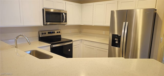 kitchen with light stone counters, sink, stainless steel appliances, and white cabinets