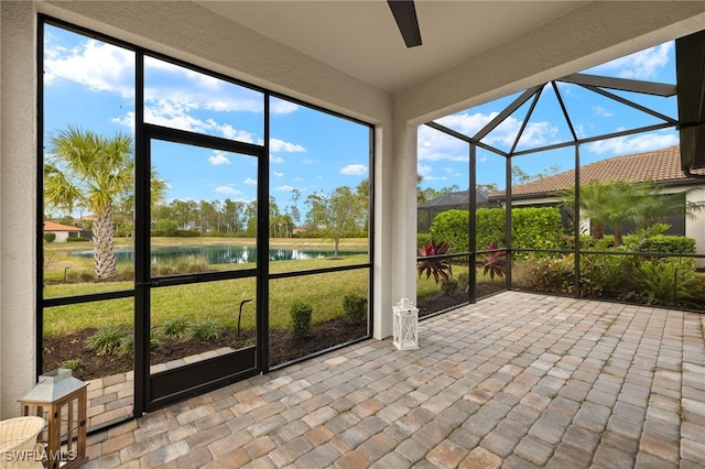 unfurnished sunroom featuring ceiling fan and a water view