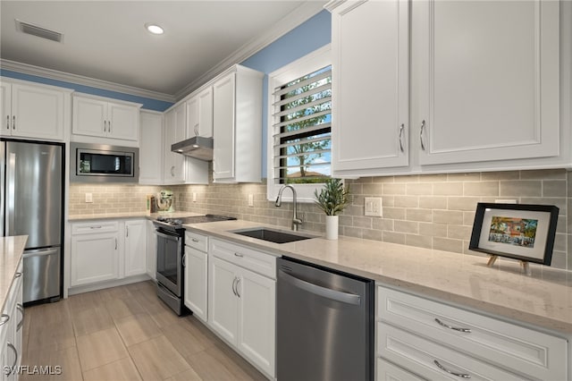 kitchen featuring sink, appliances with stainless steel finishes, light stone counters, ornamental molding, and white cabinets