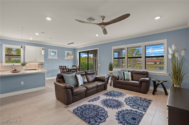 living room with crown molding, light hardwood / wood-style flooring, and ceiling fan