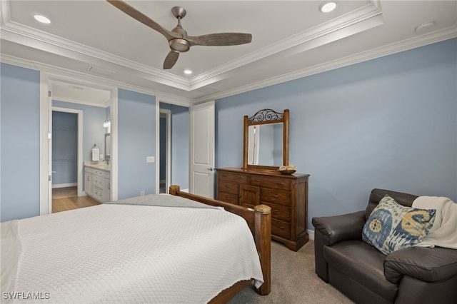 carpeted bedroom featuring ceiling fan, ornamental molding, a raised ceiling, and ensuite bath