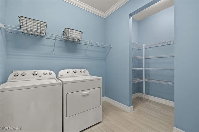 clothes washing area featuring washing machine and dryer, ornamental molding, and light wood-type flooring