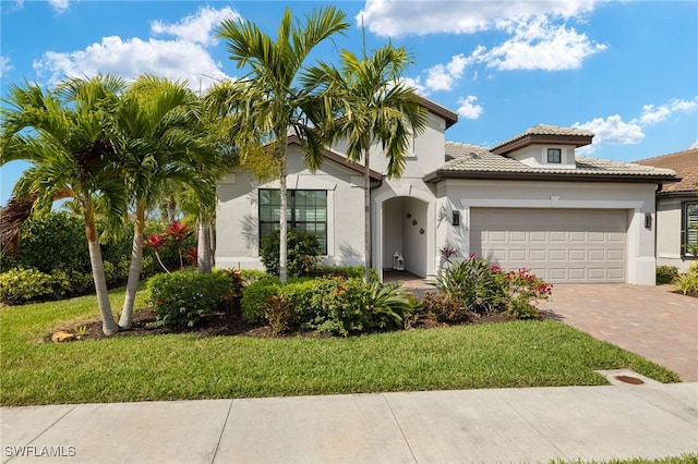 mediterranean / spanish house featuring a garage and a front lawn