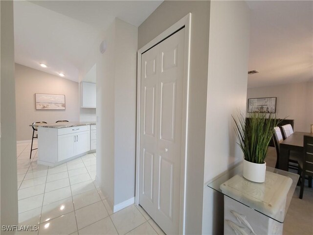 corridor with vaulted ceiling and light tile patterned flooring