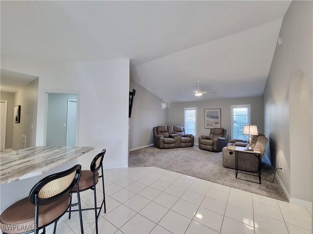 living room featuring vaulted ceiling, light carpet, and ceiling fan