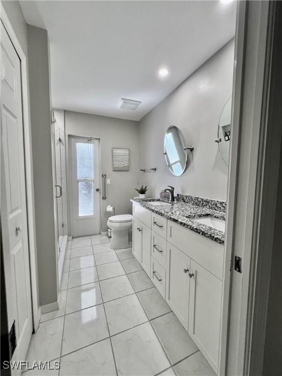 bathroom with a shower with door, vanity, and toilet