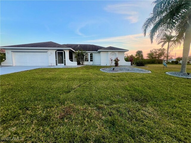 single story home featuring a garage and a yard