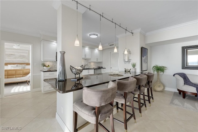 kitchen featuring white cabinetry, a kitchen bar, hanging light fixtures, and light tile patterned floors