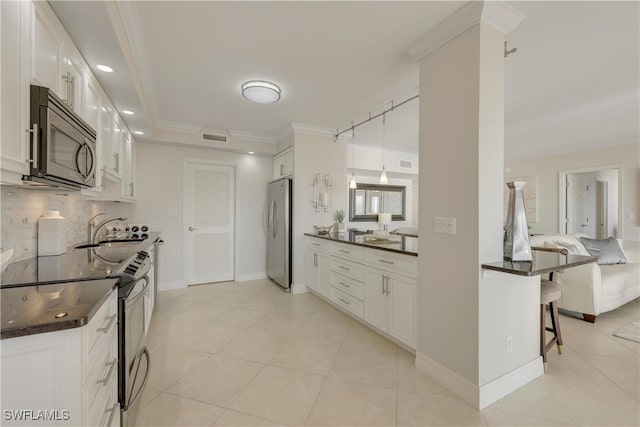 kitchen with appliances with stainless steel finishes, a breakfast bar, tasteful backsplash, white cabinetry, and sink