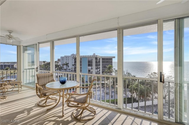 sunroom featuring ceiling fan and a water view