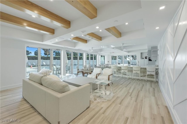 living room featuring light hardwood / wood-style flooring, beam ceiling, a wealth of natural light, and ceiling fan