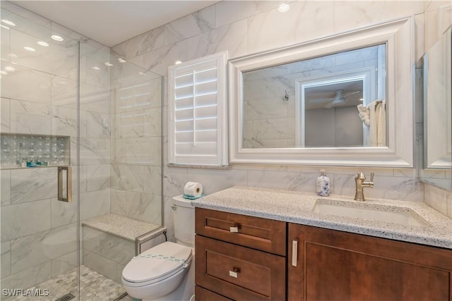 bathroom with toilet, tile walls, vanity, a shower with door, and backsplash