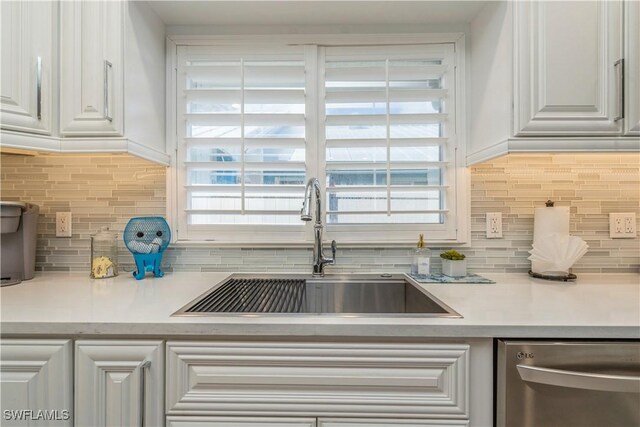 kitchen with a healthy amount of sunlight, sink, stainless steel dishwasher, and white cabinets