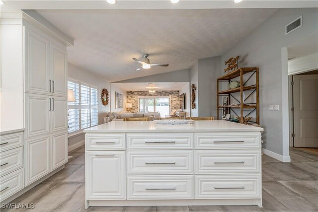 kitchen with white cabinetry, vaulted ceiling, a center island, and ceiling fan