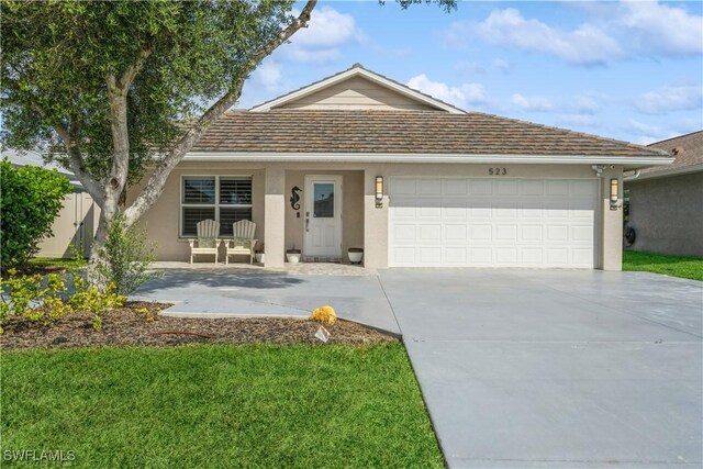 ranch-style house with concrete driveway, a front yard, an attached garage, and stucco siding