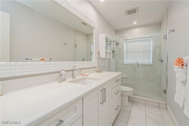 bathroom featuring vanity, a shower with shower door, tile patterned floors, and toilet