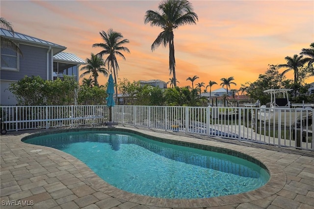 pool at dusk featuring a patio