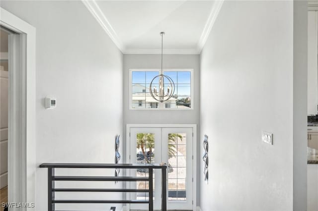 foyer entrance with crown molding, french doors, and a chandelier