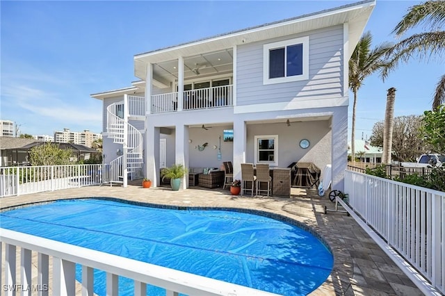 back of property with exterior bar, a covered pool, ceiling fan, and a patio area