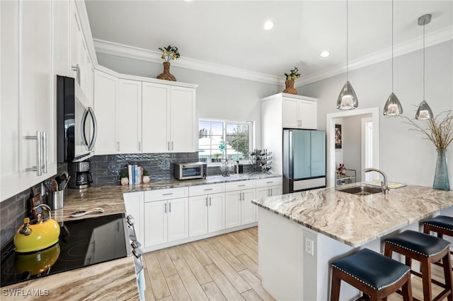 kitchen featuring pendant lighting, white cabinetry, sink, built in refrigerator, and light stone countertops