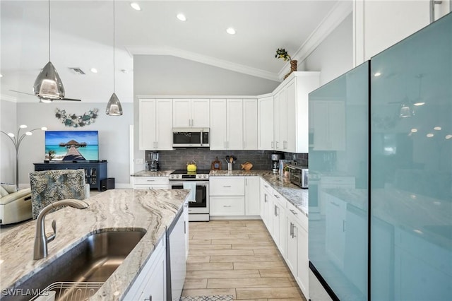 kitchen featuring sink, white cabinetry, stainless steel appliances, light stone countertops, and decorative light fixtures