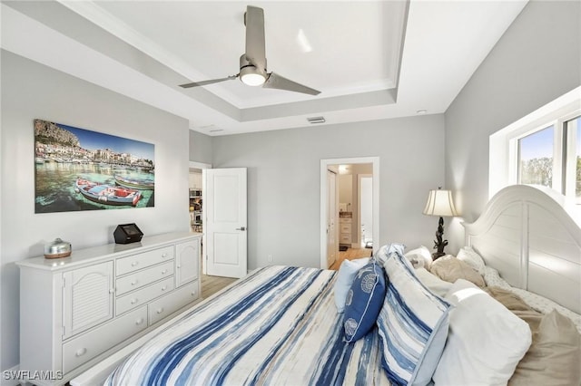 bedroom featuring connected bathroom, crown molding, a raised ceiling, and ceiling fan