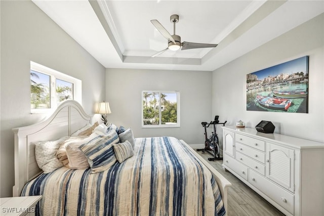 bedroom with a tray ceiling, light hardwood / wood-style flooring, and ceiling fan