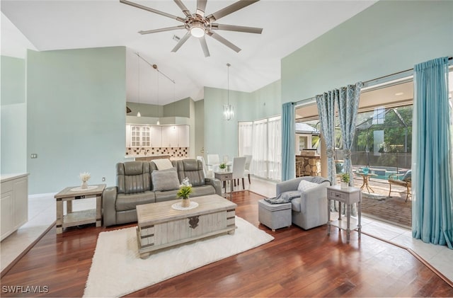 living room with dark hardwood / wood-style flooring, ceiling fan with notable chandelier, and high vaulted ceiling