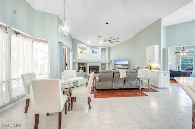 tiled dining area featuring high vaulted ceiling and ceiling fan with notable chandelier