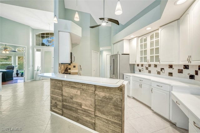 kitchen featuring high quality fridge, a towering ceiling, tasteful backsplash, white cabinets, and ceiling fan