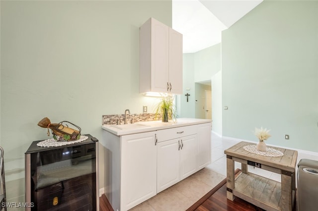 kitchen with wine cooler, sink, white cabinets, and light tile patterned flooring