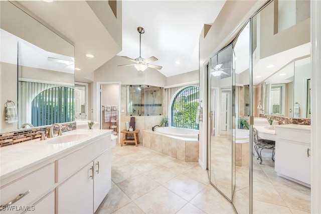 bathroom featuring tasteful backsplash, vaulted ceiling, independent shower and bath, and vanity