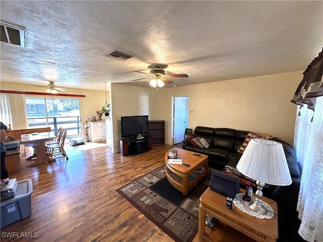 living room featuring ceiling fan, hardwood / wood-style floors, and a textured ceiling