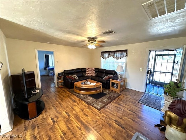 living room with ceiling fan, dark hardwood / wood-style flooring, a textured ceiling, and a wealth of natural light