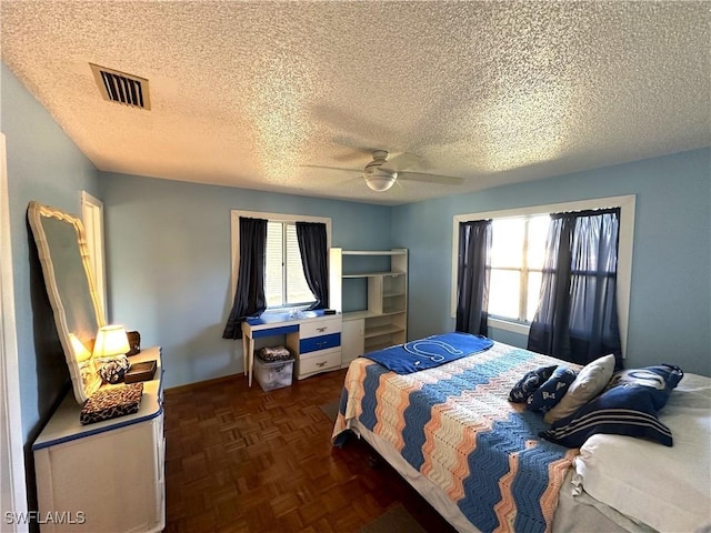 bedroom with dark parquet flooring, a textured ceiling, and ceiling fan