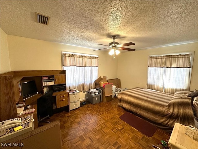 bedroom with ceiling fan, dark parquet flooring, and a textured ceiling