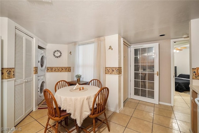 tiled dining area featuring stacked washer / dryer