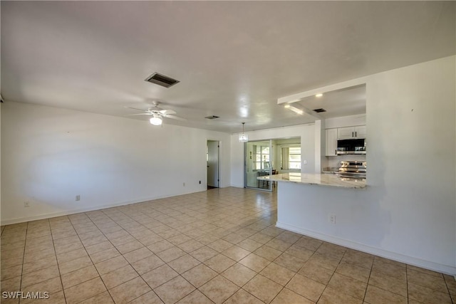 interior space with ceiling fan, appliances with stainless steel finishes, white cabinetry, light stone countertops, and kitchen peninsula