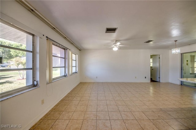 empty room with light tile patterned flooring and ceiling fan with notable chandelier