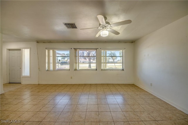 tiled empty room with ceiling fan and plenty of natural light