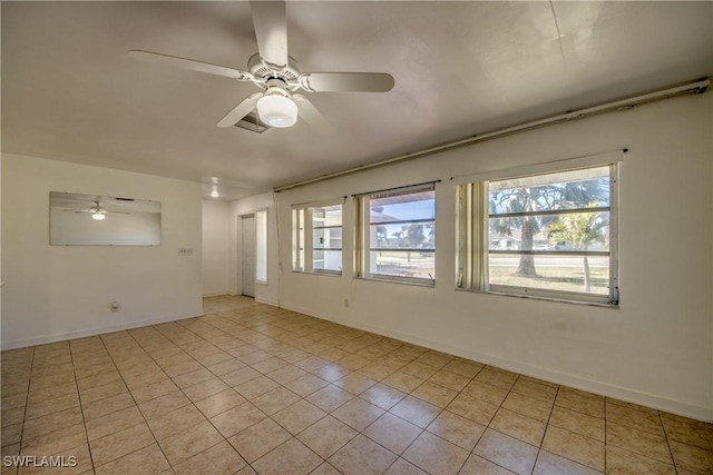 spare room with a wealth of natural light, ceiling fan, and light tile patterned floors